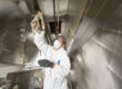 Technician performing kitchen exhaust hood cleaning at a commercial kitchen